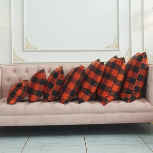 Red and black buffalo plaid pillows in seven sizes displayed on a minimalist sofa