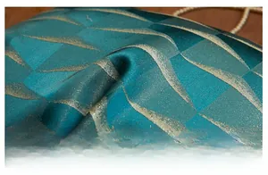 Detailed close-up of dark green jacquard pillow fabric with metallic gold geometric patterns