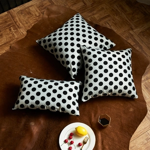 Housses de coussin à pois noir et blanc sur un tapis élégant en fourrure brune