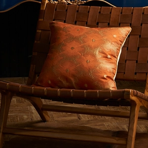 Terracotta and gold floral jacquard pillow cover on a vintage wooden chair