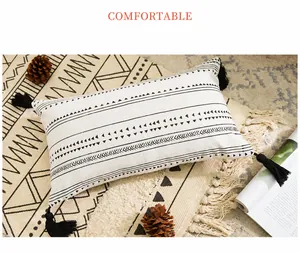 Detail of rectangular bohemian pillow cover with black geometric print and corner tassels
