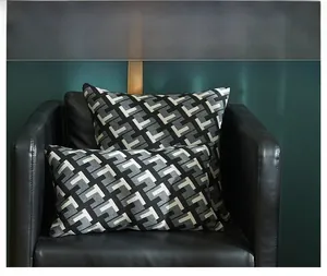 Close-up of geometric woven cushion covers in black, white, and grey on a leather sofa