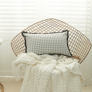Italian black and white plaid rectangle pillow cover with fringe on a gold chair