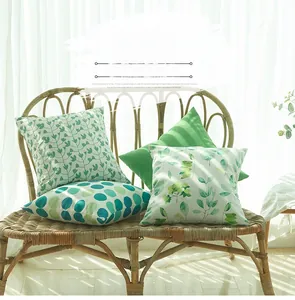 Vue détaillée de quatre taies d'oreiller à motifs verts sur une chaise en osier