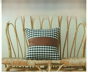 Detail of checkered fabric and brown leather patchwork on a square cushion cover