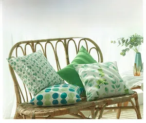 Lot de 4 housses de coussin à motifs feuilles vertes et pois sur une chaise en rotin