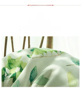 Vue détaillée du tissu en satin de haute qualité avec motifs de feuilles vertes et soie