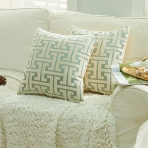 Modern chenille geometric throw pillow covers in cream and teal on a cozy sofa