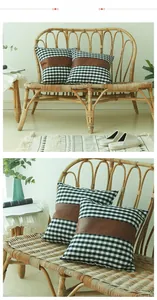 Detail of gingham pillow cover with brown faux leather patch on a rattan bench