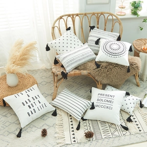Bohemian black and white printed cotton canvas pillow cover with tassels on a bamboo chair