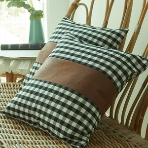 Plaid and brown faux leather patchwork square cushion covers set on a rattan chair