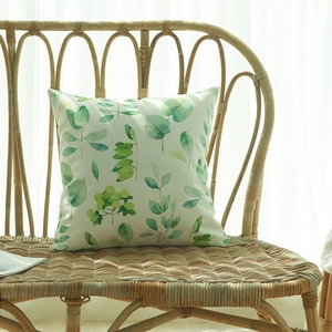 Housse de coussin imperméable à motifs feuilles vertes sur un fauteuil en rotin