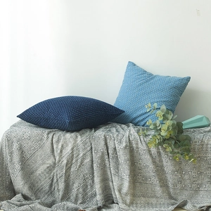 Nordic denim blue cushion covers with waffle texture on a cozy grey patterned blanket