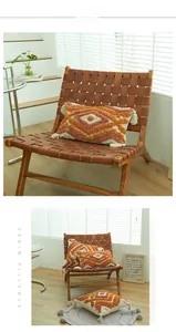 Detail of boho tufted pillowcase featuring geometric patterns and fringe on a wooden chair