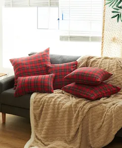 Detail of red and black plaid pillow covers and a beige textured throw on a gray sofa