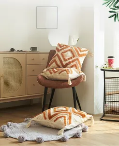 Détail du coussin touffeté géométrique avec glands orange et texture coton bohème