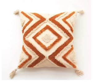 Gros plan des motifs géométriques touffetés et glands sur une housse de coussin bohème