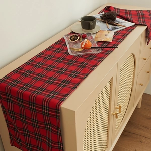 Classic red and green plaid table runner with festive woven texture on a wooden cabinet