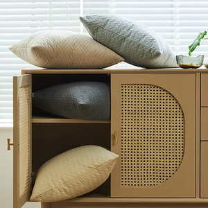 Fundas de cojín acolchadas con diseño de hojas en beige y gris sobre mueble