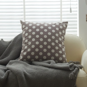 Plush taupe square pillow with white polka dots on a cozy beige sofa setting