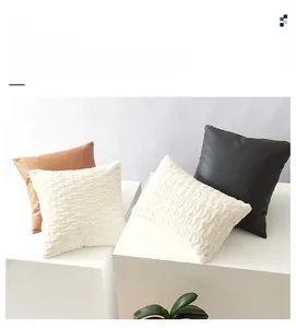 Detail of plush textured pillow covers in white, brown, and black with wave patterns