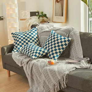 Blauw-wit schaakbord chenille sierkussens set op een moderne grijze woonkamer sofa bank