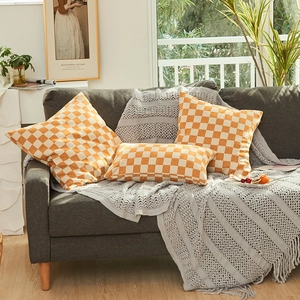 Moderne oranje en witte chenille kussens met dambordpatroon op een grijze bank