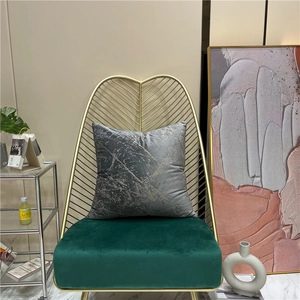 Grey velvet throw pillow with gold marble pattern on a luxury emerald green chair