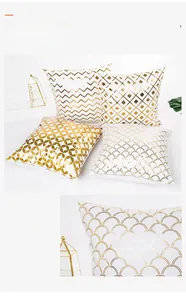 Detail of four geometric gold foil pillow covers with chevron and diamond patterns