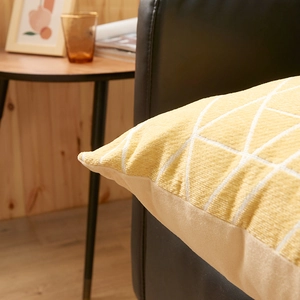 Chenille throw pillow cover with yellow geometric patterns on a black leather sofa