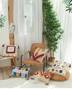 Detail of colorful tufted cushion cover with geometric patterns and bohemian tassels