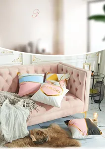 Detail of pink and gold geometric pillow covers with heart patterns on velvet sofa