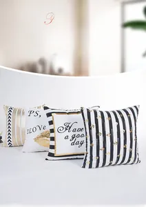 Detail of four modern throw pillow covers with metallic gold stripes and text patterns