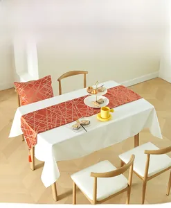 Detail of modern orange table runner with gold geometric patterns and tassels