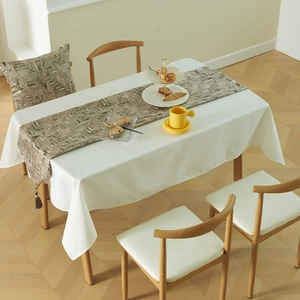 Modern geometric mosaic table runner set with tassels on a white tablecloth