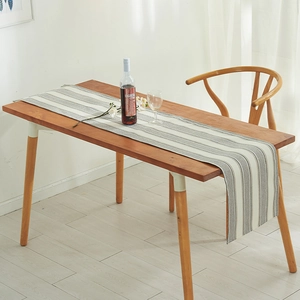 Linen cotton table runner with gray and white vertical stripes on a dark wooden dining table