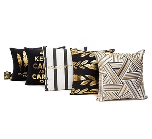 Close-up of gold leaf feather and geometric patterns on black and white pillow covers