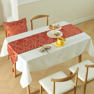 Modern orange table runner with silver geometric patterns and decorative tassels