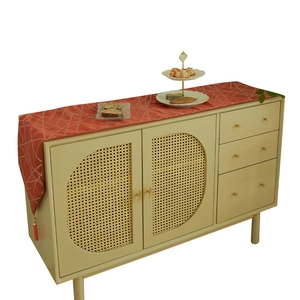 Modern orange table runner with gold geometric lines and tassels on a cream vintage cabinet