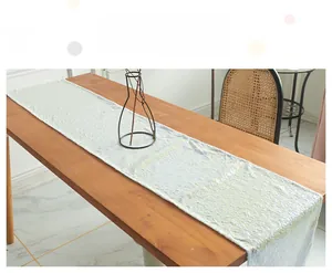 Detailed texture of white sequin table runner on a wooden dining table for modern parties