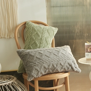 Plush geometric jacquard pillow covers in green and grey on a wooden chair
