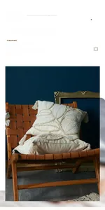 Detail of cream tufted leaf pattern pillow with decorative tassels on a leather chair