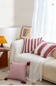 Detail of red and white striped cushion cover with soft fringe tassels on a sofa