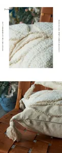 Detailed view of tufted leaf pattern and boho tassels on a minimalist cream pillow