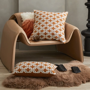 Modern orange geometric lumbar pillow and square cushion set on luxury leather chair