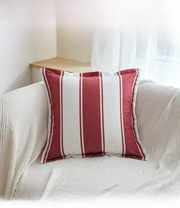 Close-up of red and white striped throw pillow with textured weave on a white sofa