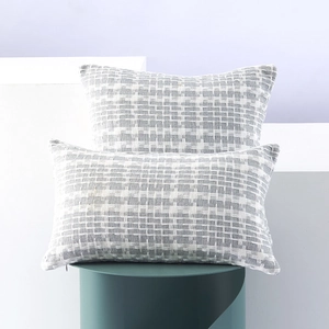 Two-piece gray and white woven lumbar pillow covers on decorative geometric stands