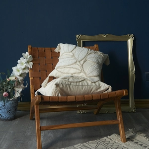 Bohemian cream tufted leaf pillow covers with tassels on a brown leather chair