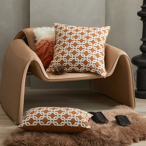 Modern geometric caramel orange cushion covers set on a leather chair and rug