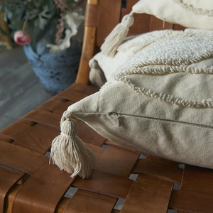 Bohemian off-white tufted leaf pillowcase with handmade tassels on a vintage leather chair